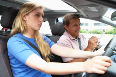 Learning to drive is a great analogy for the skills of a life coach. A skilful coach will always let the client be in the drivers seat and taking responsibility for the actions they take. Young woman learning to drive with driving instructor.